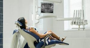 Patient sitting on dental chair wearing dental bib