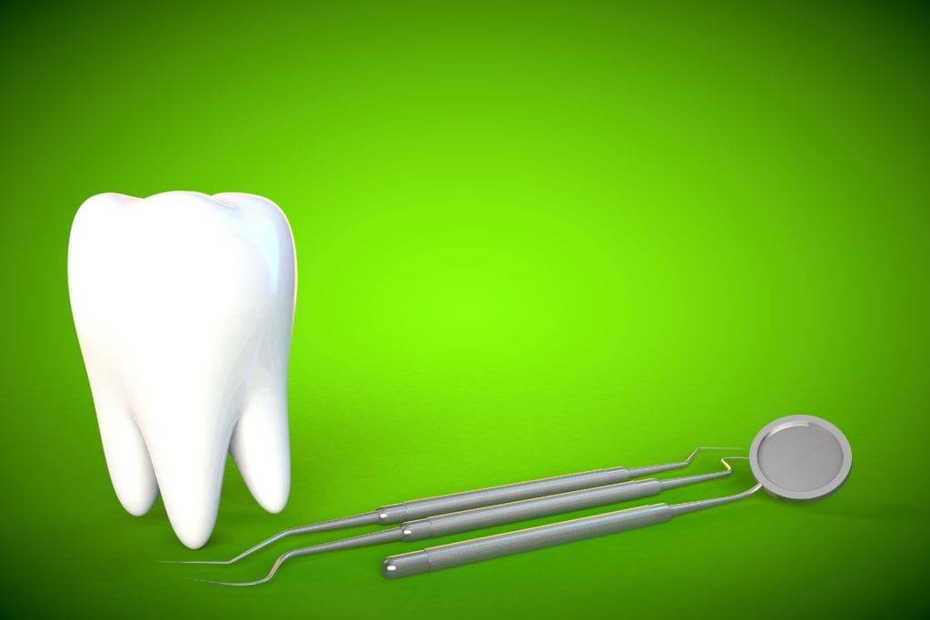 Giant tooth and dental mirror on a green background